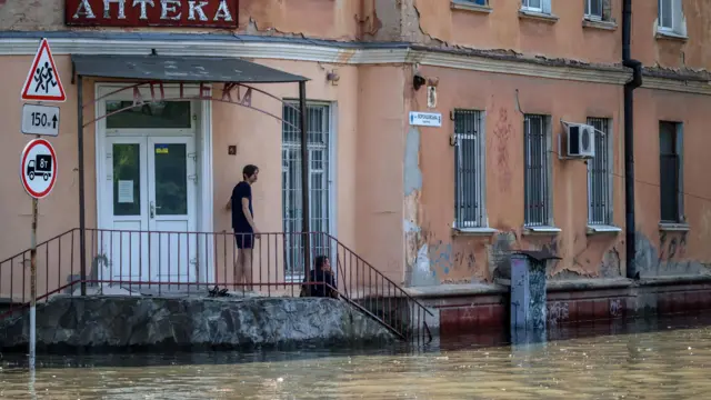 A man looks on at a flooded area in Kherson