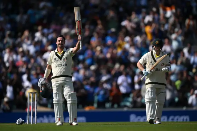 Travis Head raising his bat after scoring his century as Steve Smith applauds