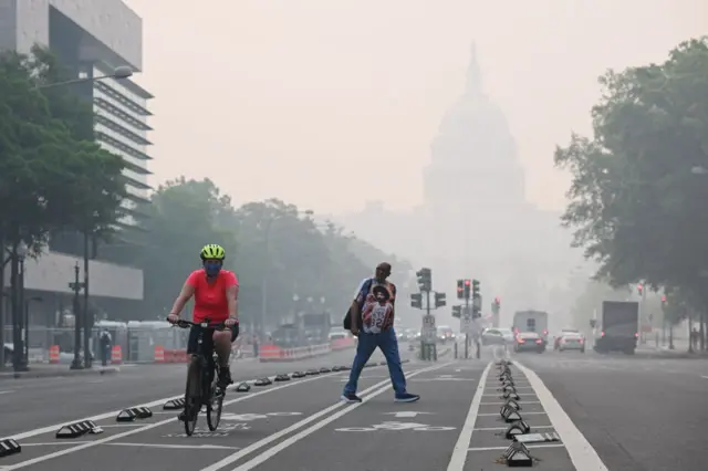 A cyclist rides under a blanket of haze partially obscuring the US Capitol in Washington DC, on 8 June 2023