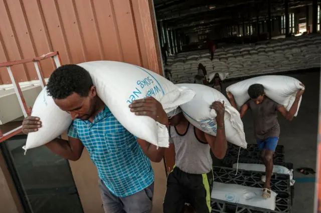 Workers carry sacks of grain in a warehouse of the World Food Programme (WFP) in the city of Abala, Ethiopia, on June 9, 2022.