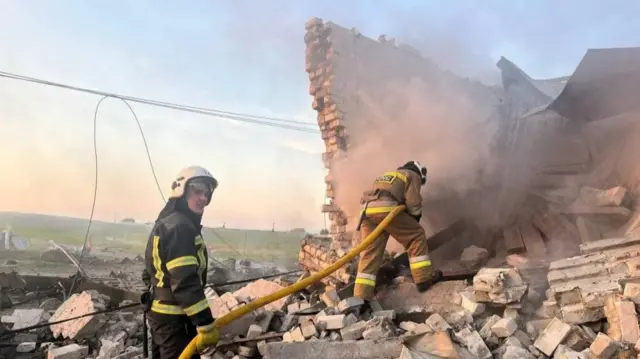 Firefighters work at a site of a car wash heavily damaged by a Russian missile strike