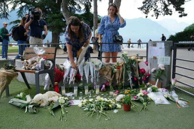 People lay flowers and tributes for the victims of the attack in a park in Annecy, France