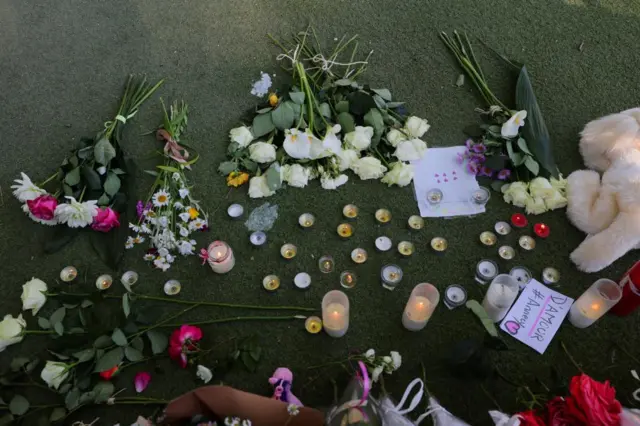 Floral and candle tributes and handwritten notes left on the ground