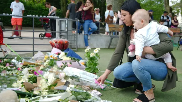 A mother, carrying her baby, visits the scene