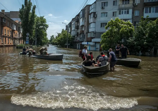 Rescuers evacuate local residents from a flooded area after the Nova Kakhovka dam breached