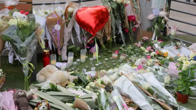 Flowers, candles and a heart-shaped balloon laid out on the ground