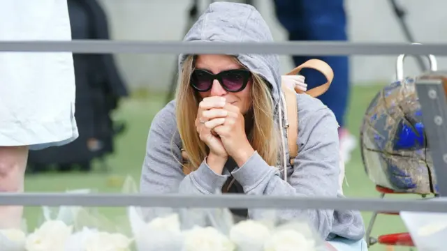 A woman cries as she kneels before the tributes