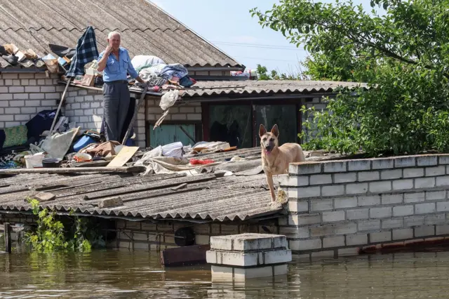 A local resident on the roof of his house in the flooded area of Kherson, Ukraine,