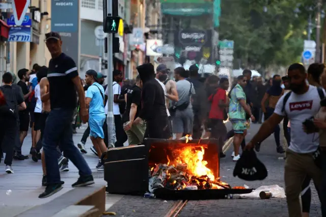 Protesters walk past a burnt out rubbish bin during clashes with police in Marseille, southern France, on 1 July 2023