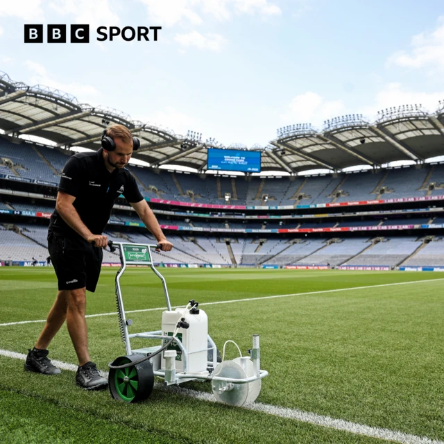 A groundsman prepares the pitch markings ahead of the game