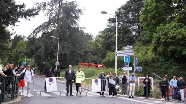 People wait next to the entrance of the Mont-Valérien cemetery, where Nahel M has been laid to rest, in Nanterre, near Paris, France, on 1 July 2023.