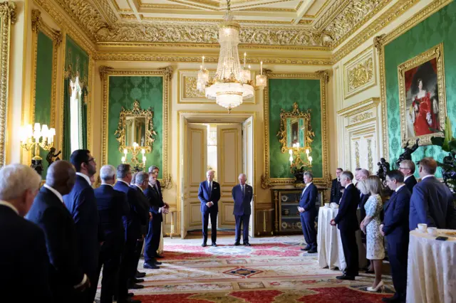 Joe Biden, King Charles, and several business leaders in an ornate room