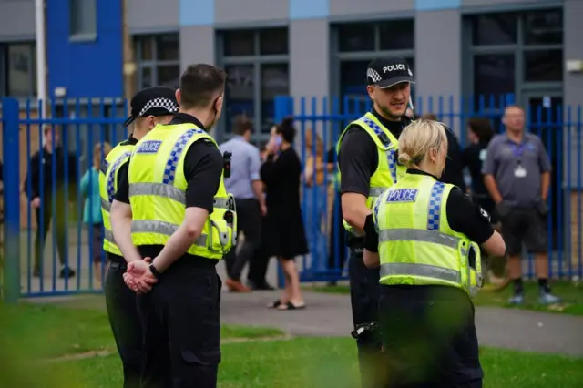 Police remain outside the school, as pupils continue to leave