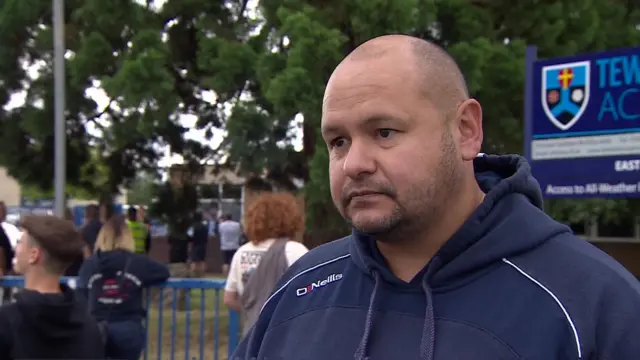 A father stands outside the school gates