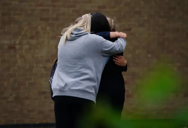 People hugging outside the school gates