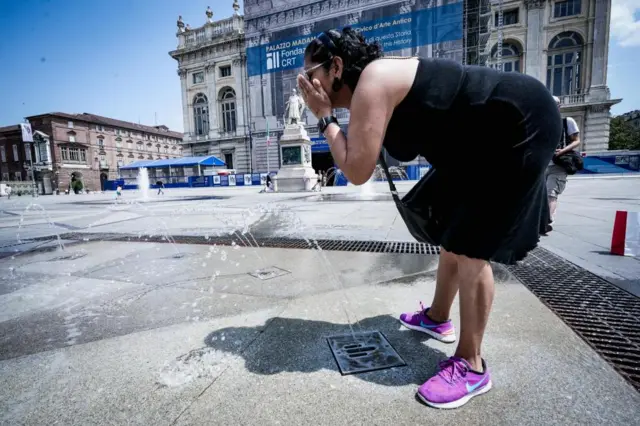 A person cools off in a fountain of Piazza Castello amid high temperatures in Turin, northern Italy, 11 July 2023.