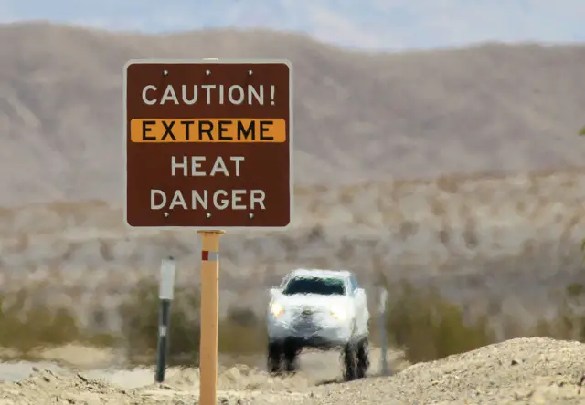 Heat waves rise near a heat danger warning sign on the eve of the AdventurCORPS Badwater 135 ultra-marathon race on July 14, 2013 in Death Valley National Park, California