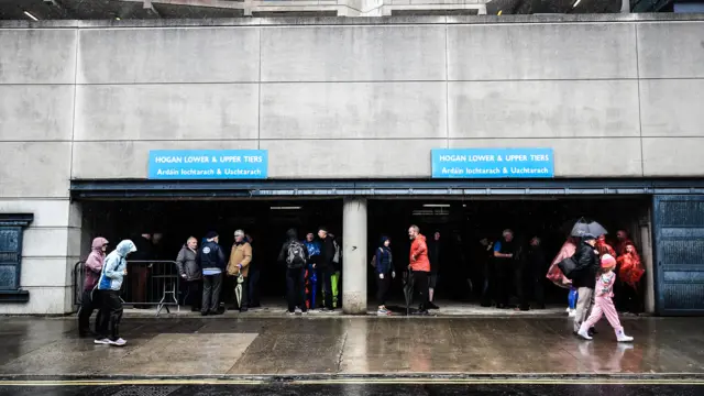 Fans shelter from the rain ahead of the game