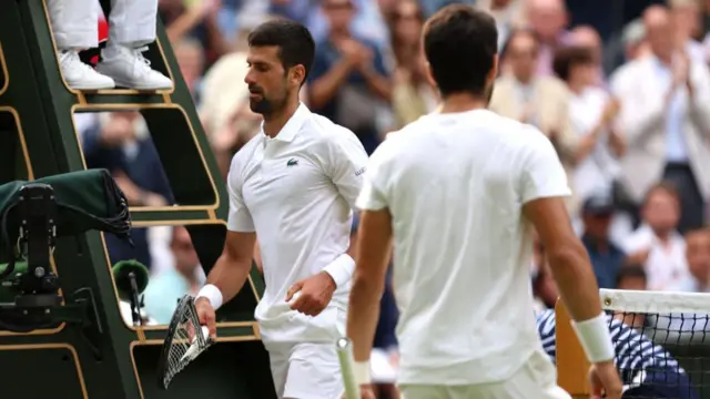 Djokovic holds a broken racquet