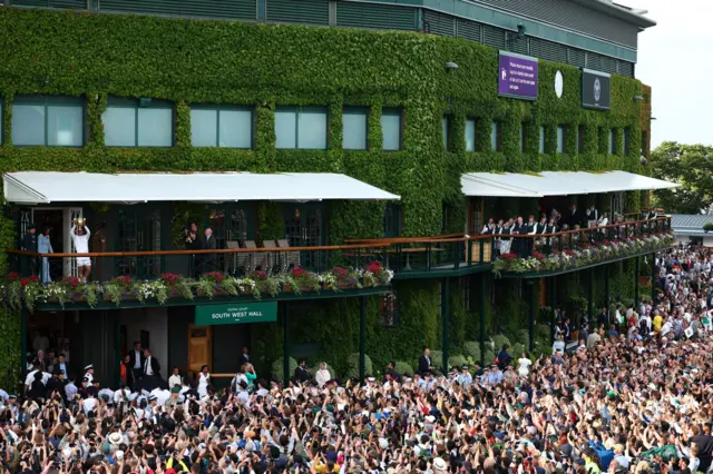 Wide angle of crowds outside Centre Court watching Carlos Alcaraz lift the Wimbledon trophy