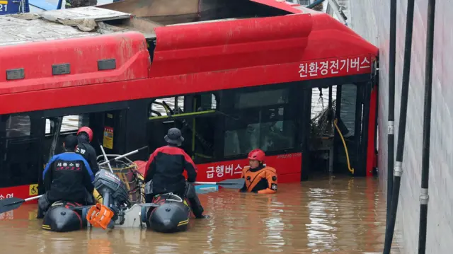 A bus is brought out of a flooded underground tunnel after flood water submerged 15 vehicles in the central town of Osong, South Korea