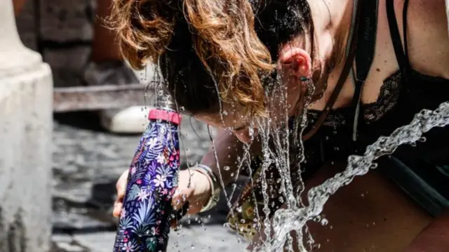 Woman dousing head in water in Italy