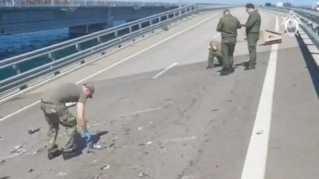 Russian investigators work at the scene, on a section of damaged bridge heavily sloping to the left