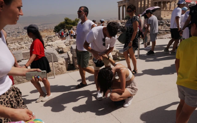 A visitor is affected by the heat atop the Acropolis hill, during a heatwave in Athens