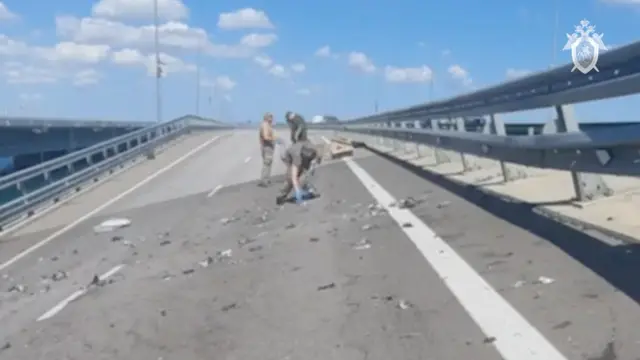 Russian investigators work at the scene, on a section of damaged bridge heavily sloping to the left