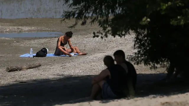 A woman reads a book at the Lido beach on the river Danube in Belgrade, Serbia, 17 July 2023. Serbia's Hydrometeorological Service issued a warning on high temperatures of up to 40 degrees Celsius in the following days.