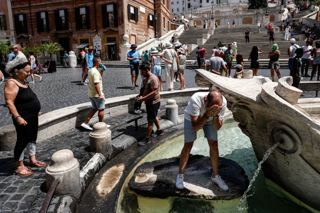 People using the water fountain in Rome