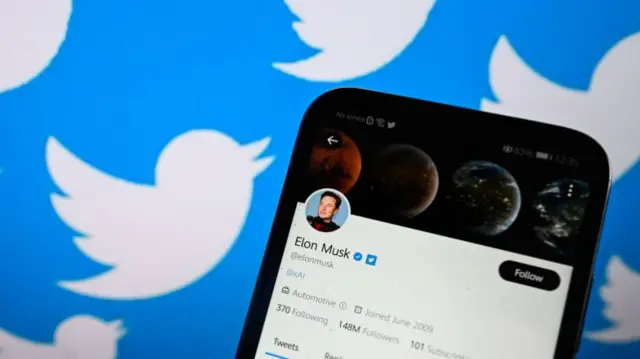 Twitter owner Elon Musk's Twitter account is displayed on a smartphone with Twitter logo on the background