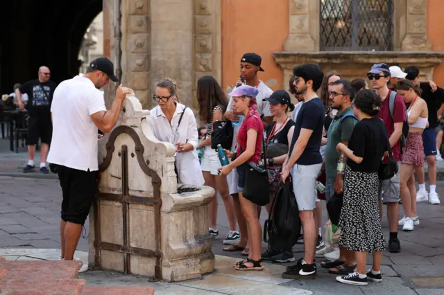 People queue at a water fountain in Bologna, Italy