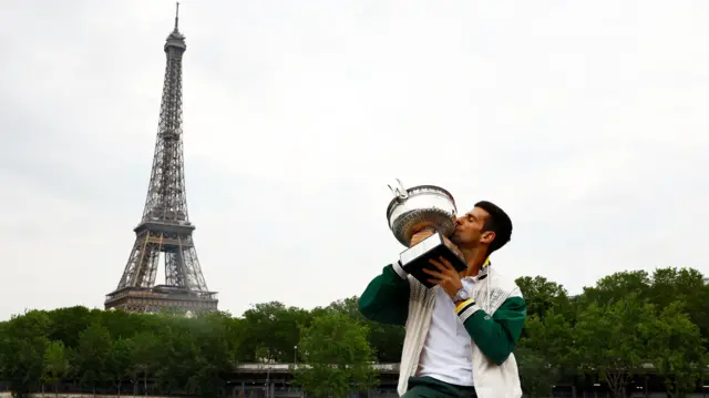 Novak Djokovic holds the French Open trophy in front of the Eiffel Tower in Paris