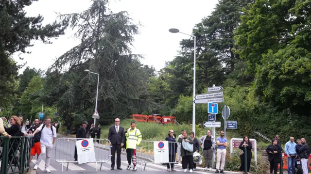 People wait next to the entrance of Mont Valerien cemetery, before Nahel's burial