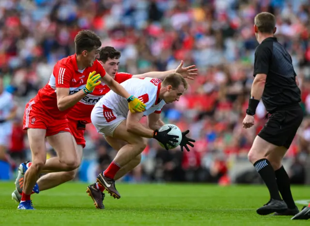 Matty Taylor of Cork as he is tackled by Padraig McGrogan and Paul Cassidy of Derry