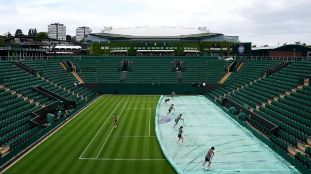 Wimbledon ground staff putting covers on a court