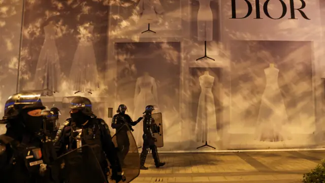 Police officers stand guard in front of the Dior building during riots at the Champs-Élysées in Paris, France, 1 July 2023