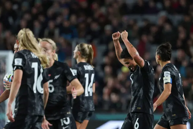 New Zealand player's stretch their arms into the air in relief.