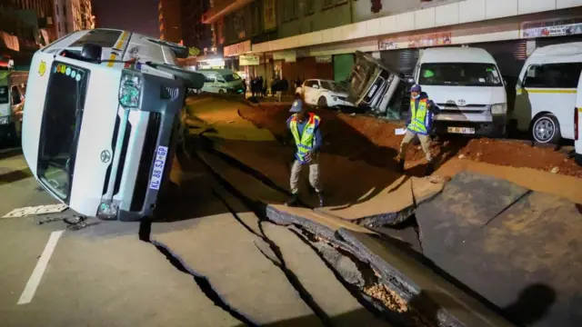 Police officers inspect damaged cars and the road after a suspected gas explosion injured people and caused significant damage, in the central business district of Johannesburg, South Africa July 19, 2023.