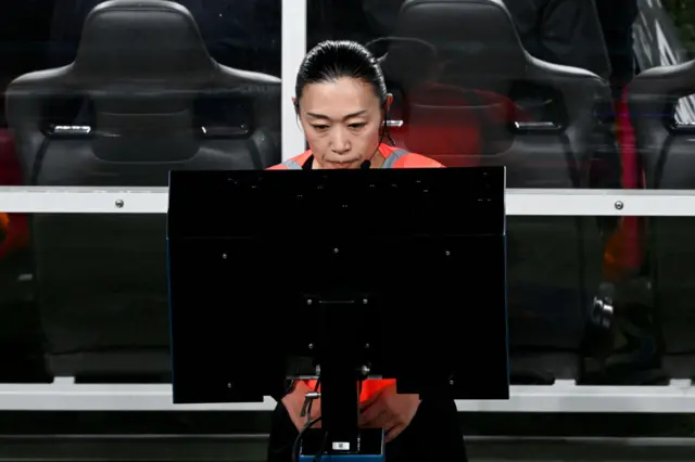 The referee goes to the pitchside monitor to check a penalty incident.