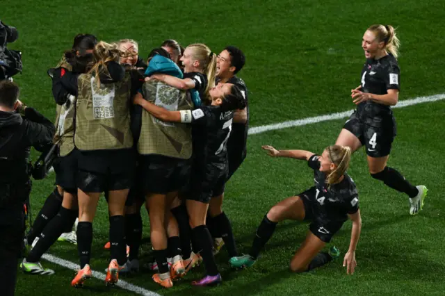 New Zealand players huddle together to celebrate their goal.