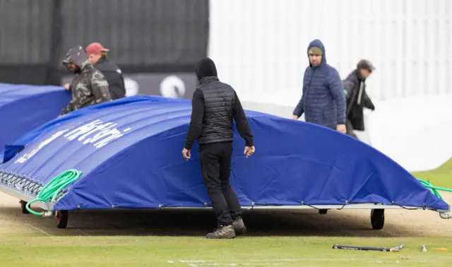 Groundskeepers scramble to get the covers on