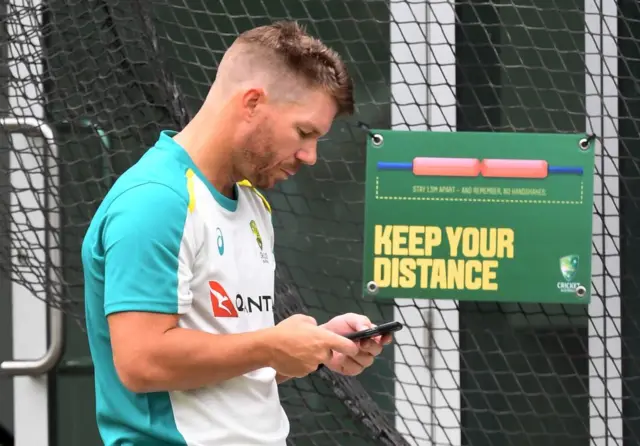 David Warner looking at a mobile phone