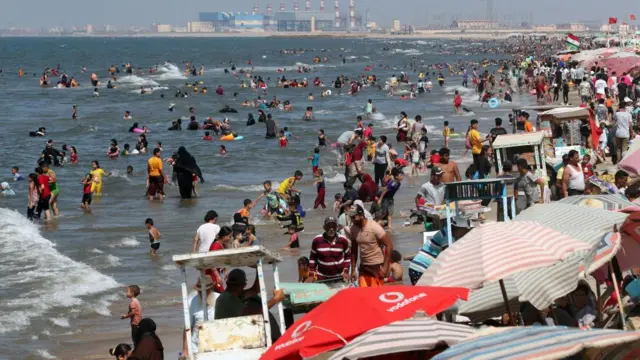 athers swim in the sea as others shelter under sunshades at the beach during hot weather at Gamasa Beach near Mansoura, north of Cairo, Egypt, 20 July 2023