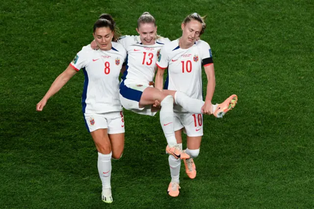 Norway players carry their teammate off the pitch to try and get on with the game.