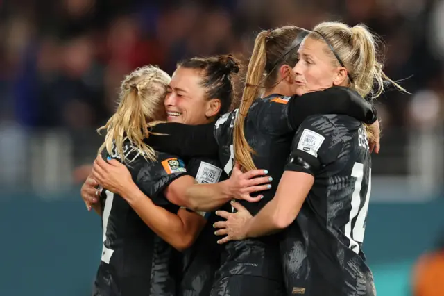 New Zealand players embrace each other after securing a historic win.