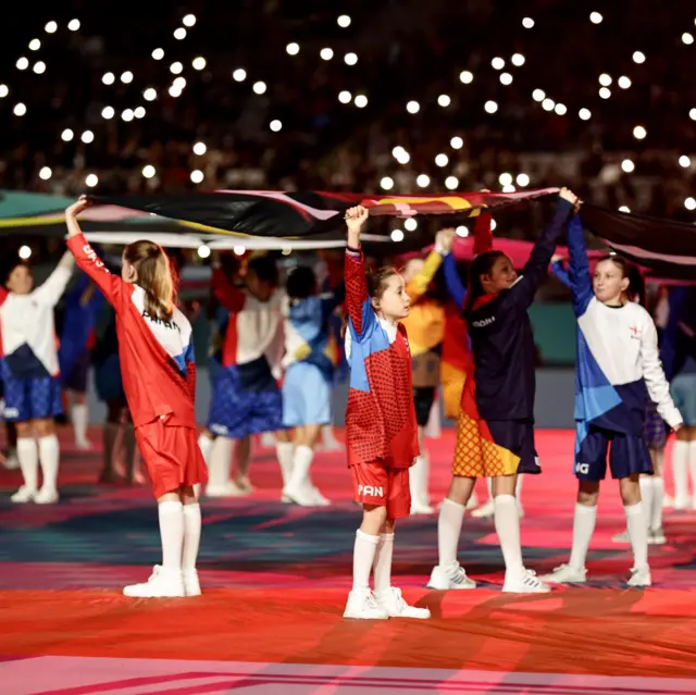 Dancers hold up a banner in the opening ceremony.