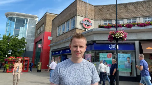 Paul Burn poses in front of Uxbridge Underground station