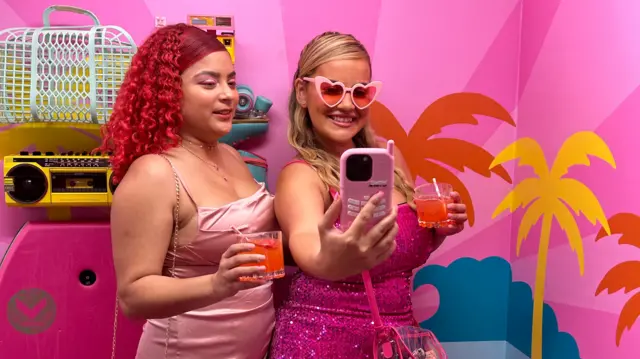 Two women pose in pink outfits for Barbie event